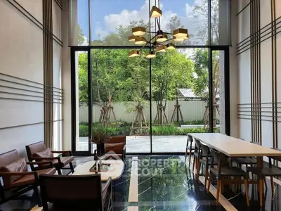 Luxurious modern living room with floor-to-ceiling windows and stylish furniture overlooking a lush garden.