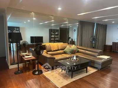 Spacious living room with elegant leather sectional sofa and mirrored wall, perfect for modern living.