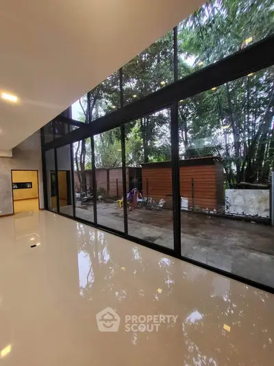 Spacious modern living room with floor-to-ceiling windows and garden view