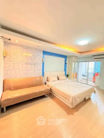 Spacious modern bedroom with stylish decor and natural light, featuring a cozy bed and comfortable seating area.