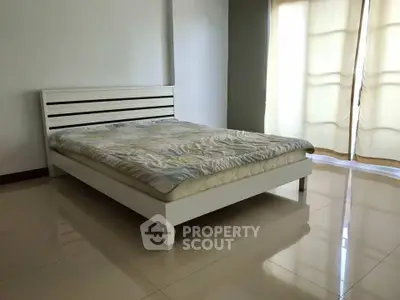 Spacious bedroom with modern bed and large windows for natural light.