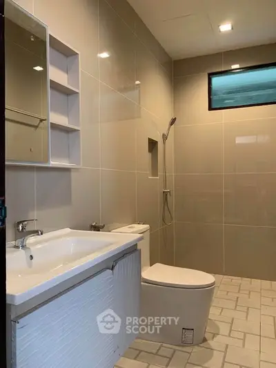 Modern bathroom with sleek fixtures and neutral tiles, featuring a spacious shower area and contemporary design.