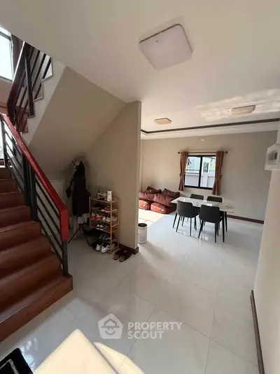 Spacious living area with modern staircase and dining set, perfect for family gatherings.