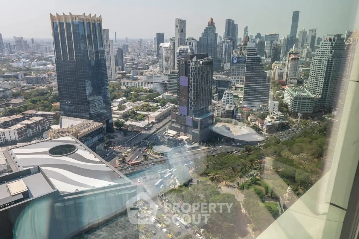 Stunning cityscape view from a high-rise building, showcasing urban skyline and lush greenery below.