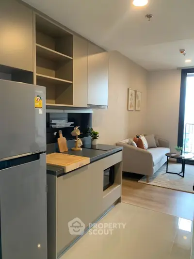 Modern open-layout kitchen with sleek appliances and cozy living area in stylish apartment.