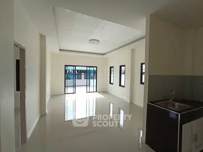 Spacious open-plan living room with large windows and modern kitchen area.