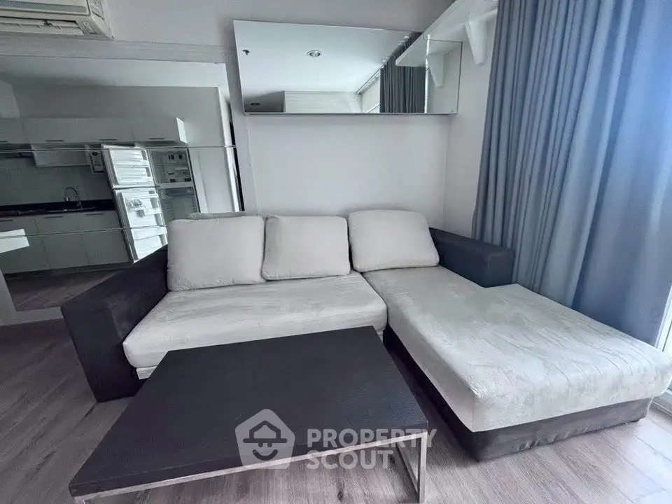Modern living room with L-shaped sofa and sleek coffee table, featuring a mirrored wall and stylish decor.