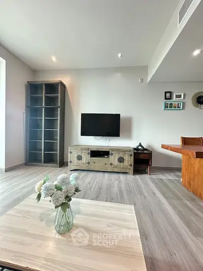 Modern living room with stylish decor and mounted TV, featuring elegant flooring and cozy ambiance.