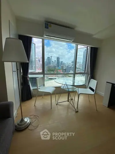 Modern living room with city view, featuring sleek furniture and large windows for natural light.