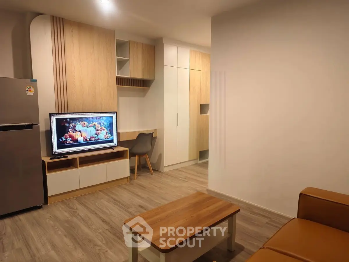 Modern living room with stylish furniture and built-in storage, featuring a sleek TV setup and cozy seating area.