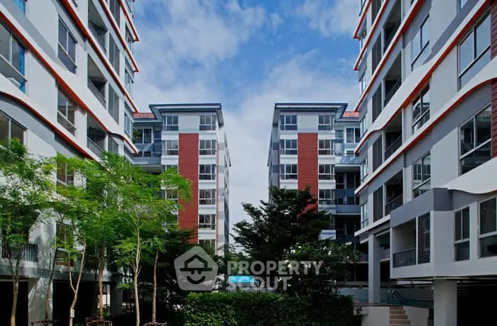 Modern apartment buildings with lush greenery and clear blue sky.