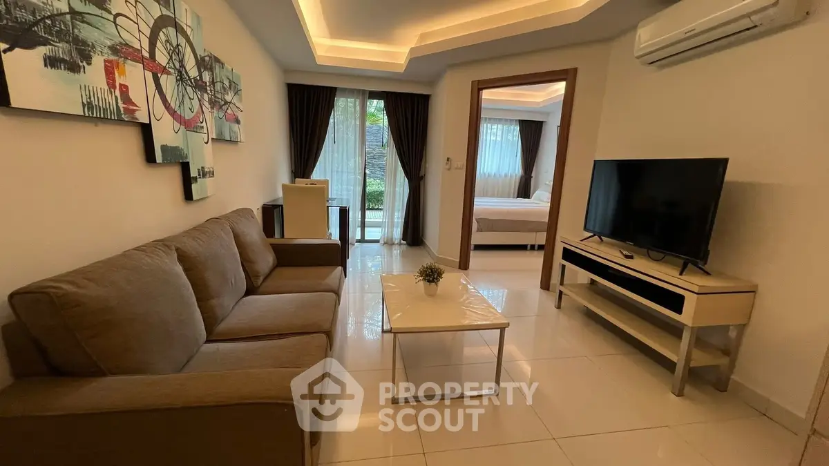Modern living room with stylish decor and natural light, featuring a cozy sofa and flat-screen TV.
