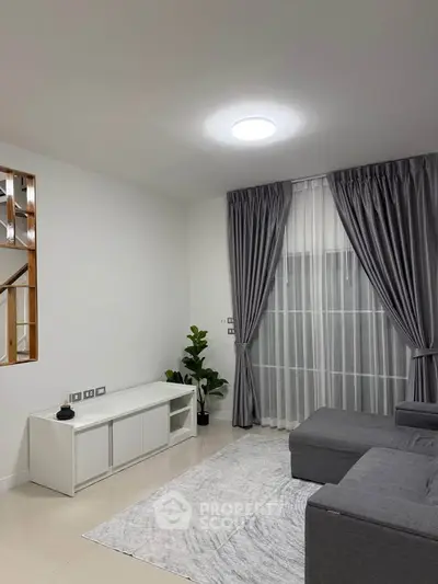 Modern living room with sleek gray sofa and elegant curtains
