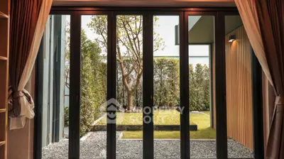 Elegant garden view from modern living room with large glass doors.