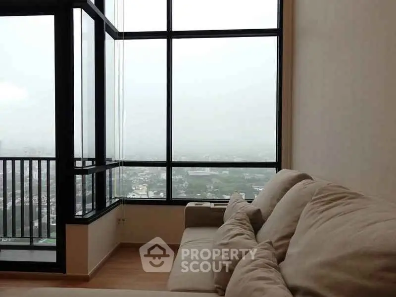 Spacious living room with large windows offering stunning city views.