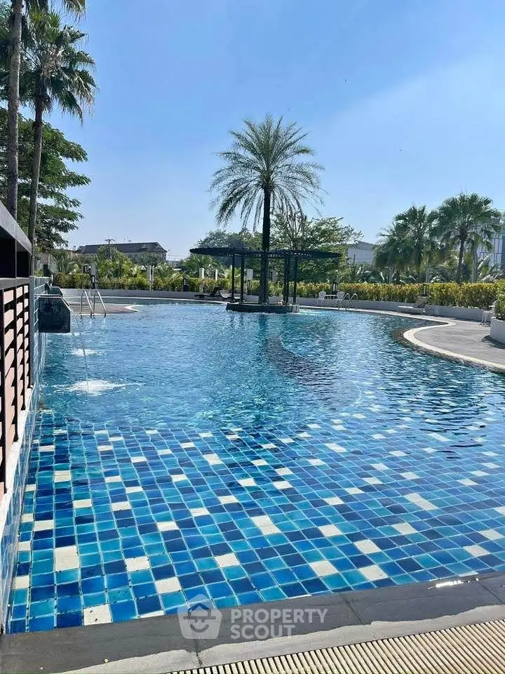 Luxurious outdoor pool with palm trees and clear blue sky in a serene setting.