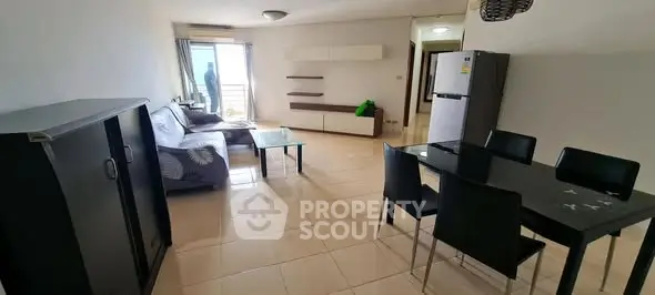 Spacious living room with modern furniture and dining area, featuring a balcony view.