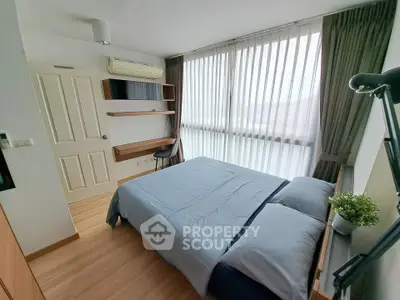 Modern bedroom with large window and stylish decor in a cozy apartment.