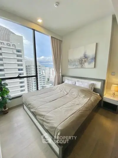 Modern bedroom with large window offering stunning city view in high-rise apartment.