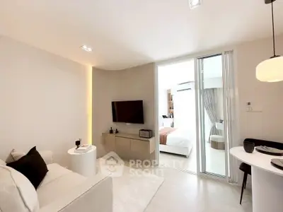 Modern living room with sleek design and open layout leading to a cozy bedroom.