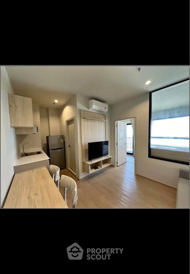 Modern apartment interior with open layout, featuring a kitchen, dining area, and living space with natural light.