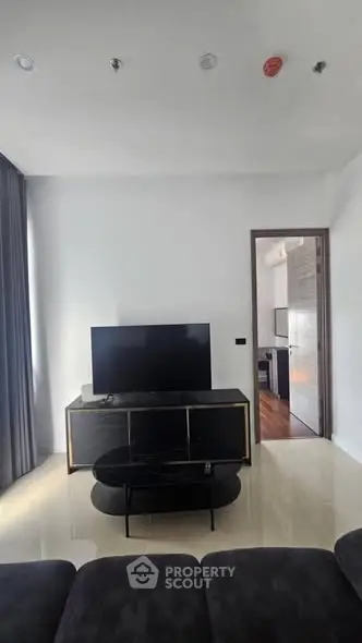 Modern living room with sleek TV stand and open doorway to kitchen area.