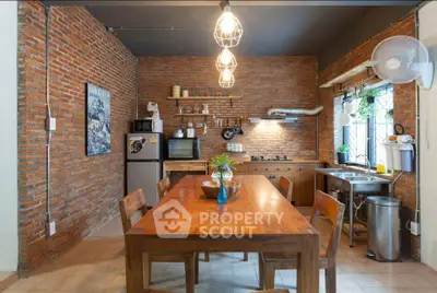 Charming rustic kitchen with brick walls and wooden dining table, featuring modern appliances and open shelving.