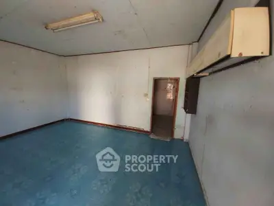 Spacious empty room with blue flooring and air conditioning unit, ideal for customization.