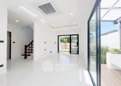 Spacious modern living room with large windows and sleek staircase in a bright, airy home.