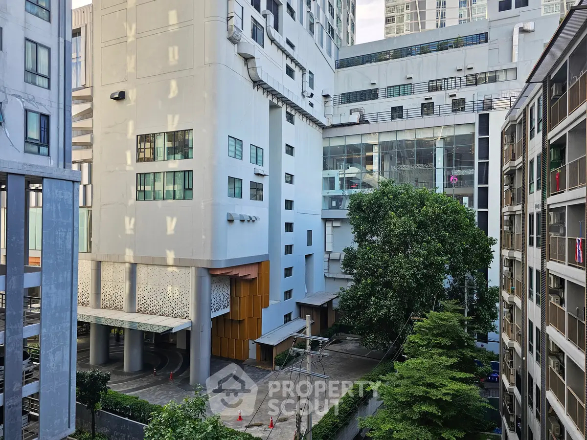Modern urban apartment complex with lush greenery and spacious outdoor area.
