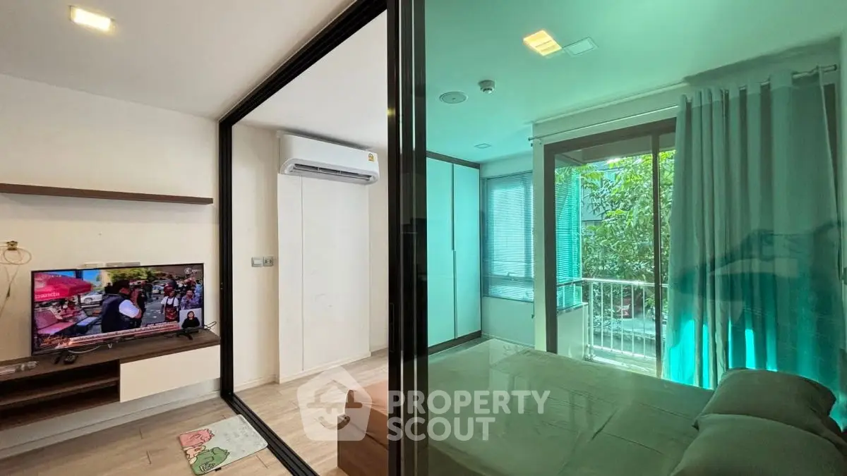 Modern apartment with glass partition, cozy living area, and bedroom with balcony view.