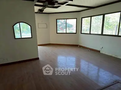 Spacious empty room with large windows and wooden flooring, ideal for customization.