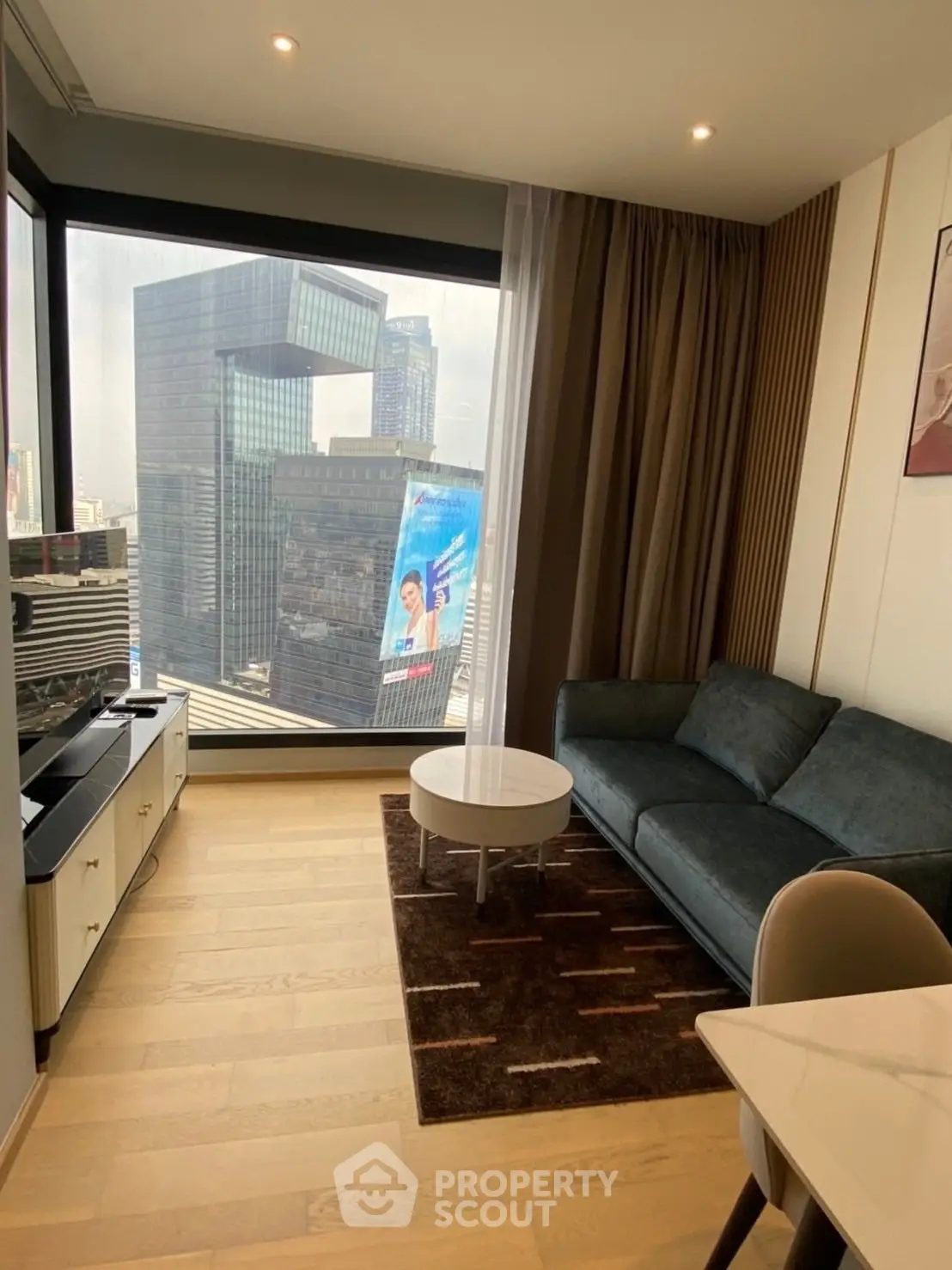 Modern living room with stunning city view, featuring sleek furniture and large windows in a high-rise apartment.