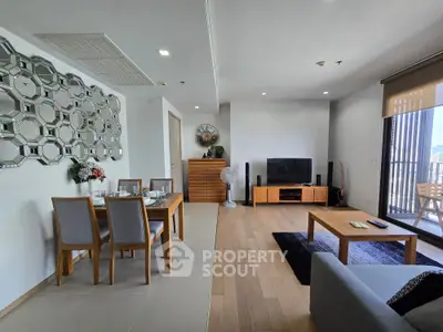 Spacious modern living room with dining area and balcony view, featuring elegant decor and ample natural light.