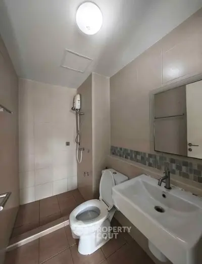 Modern bathroom with sleek fixtures and neutral tiles, featuring a shower and large sink area.