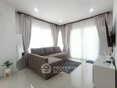 Modern living room with sleek gray sofa and elegant curtains in bright natural light.