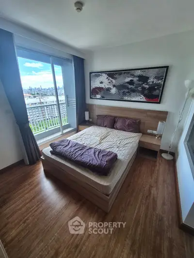 Modern bedroom with city view, featuring wooden flooring and stylish decor.