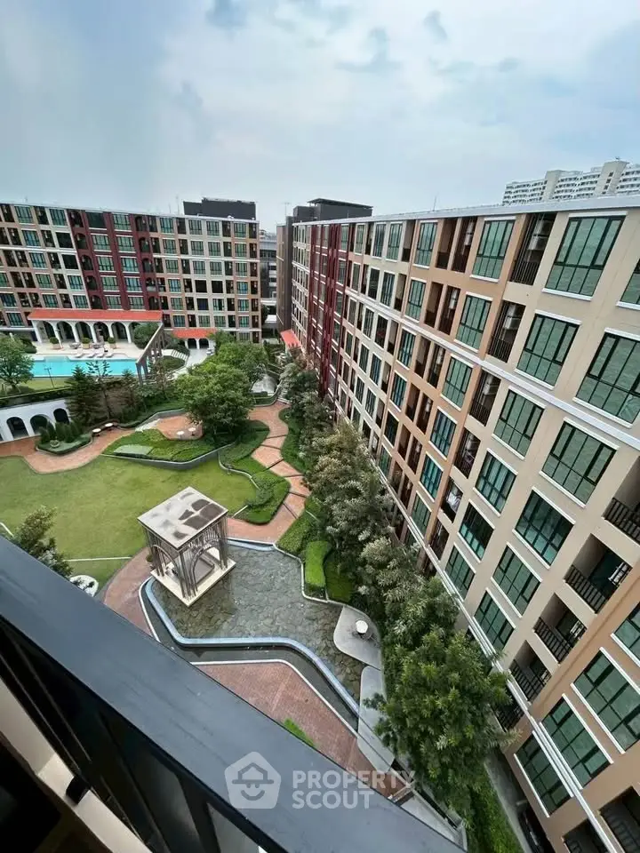Stunning aerial view of modern apartment complex with lush gardens and pool, perfect for urban living.