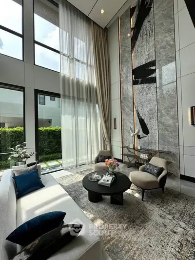 Luxurious living room with high ceilings, large windows, and modern decor in a stylish home.