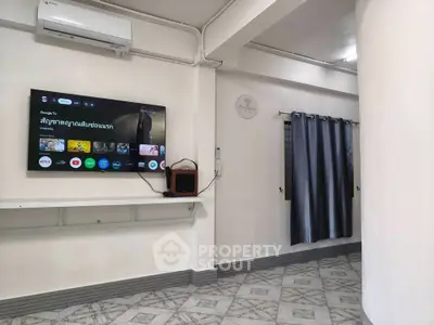 Modern living room with wall-mounted TV and air conditioning, featuring stylish curtains and tiled flooring.