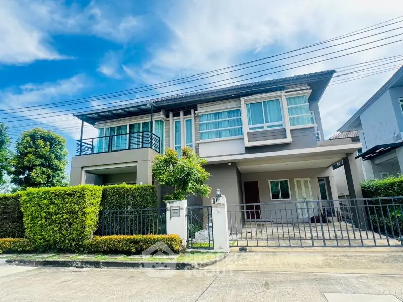 Modern two-story house with large windows and manicured garden in a suburban neighborhood.