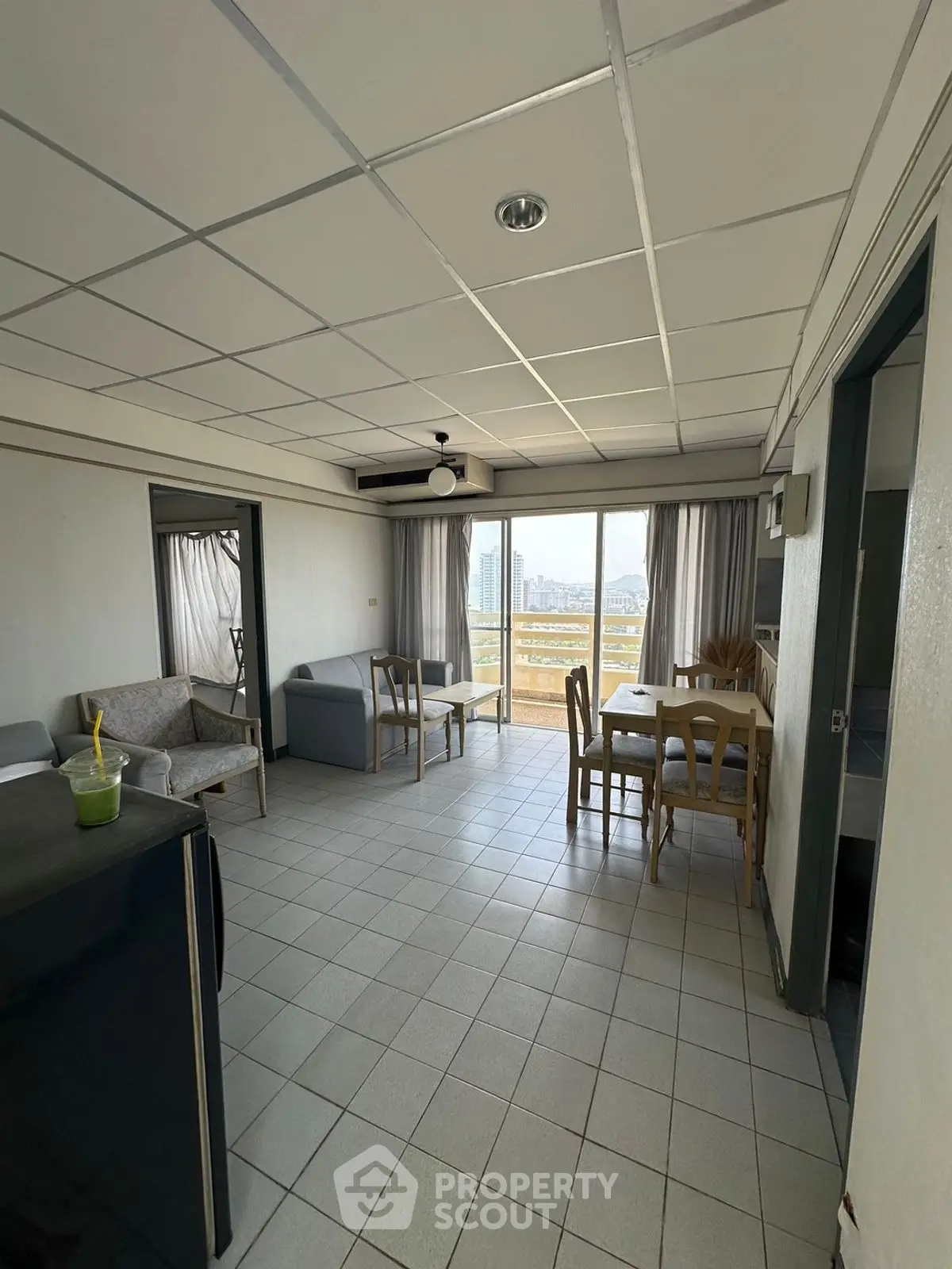 Spacious living room with city view and tiled flooring, featuring cozy seating and dining area.