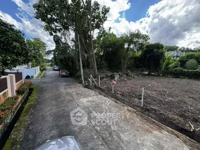 Vacant land plot with lush greenery and clear skies, ideal for development.