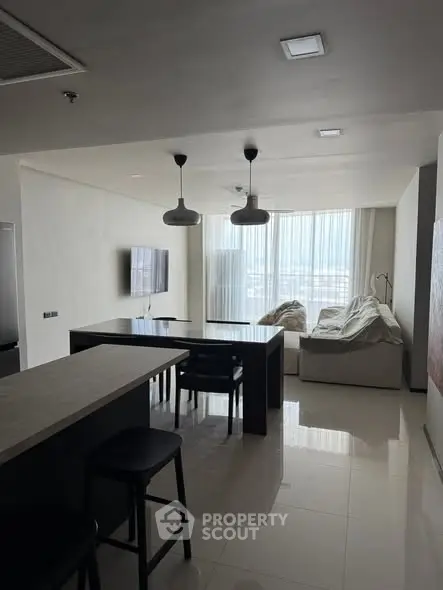 Modern living room with sleek furniture and large windows offering natural light.