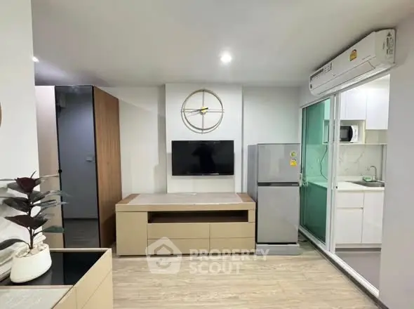 Modern living room with sleek design, featuring a wall-mounted TV and compact kitchen area.