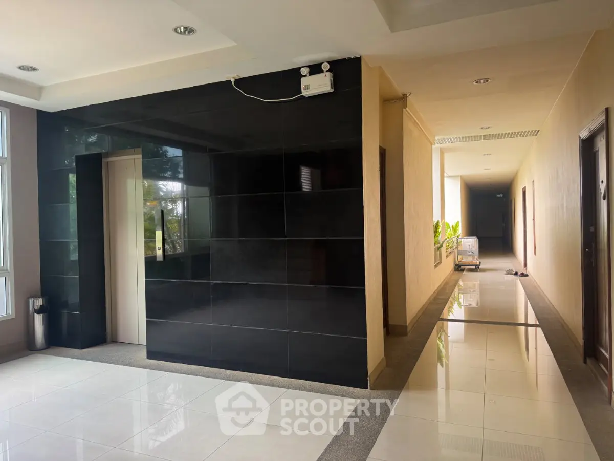 Modern building corridor with sleek elevator and polished tile flooring