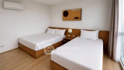 Spacious bedroom with two beds and modern decor in a bright apartment.