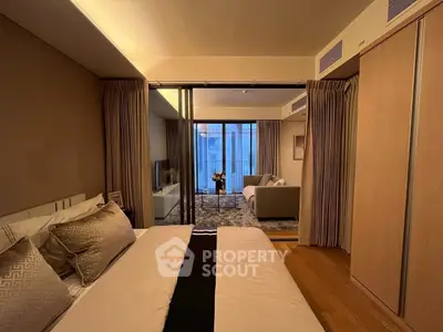 Luxurious bedroom with sliding doors leading to a cozy living room, elegant decor and warm lighting.