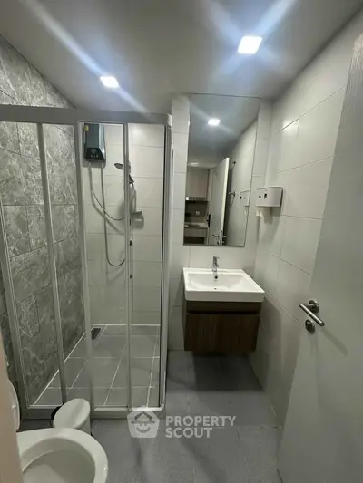 Modern bathroom with sleek shower enclosure and stylish vanity in contemporary apartment.