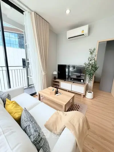Modern living room with stylish decor, large TV, and balcony access in a high-rise apartment.
